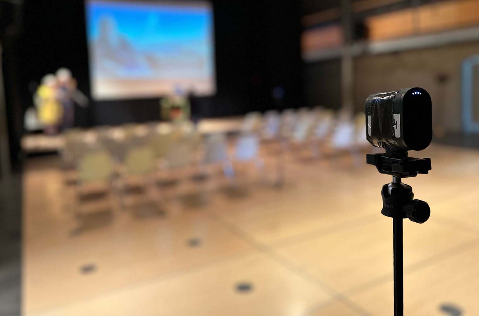Small discreet wireless camera on a tripod capturing a ceremony in a hall